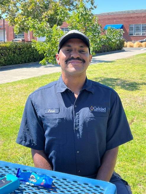 Smiling man sitting at a picnic table.